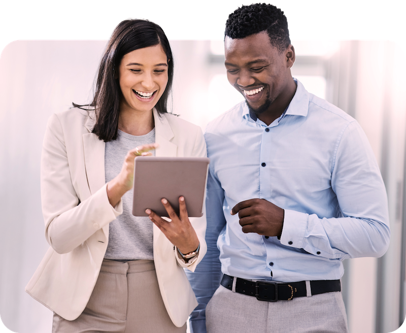 Two office workers smiling and looking at tablet