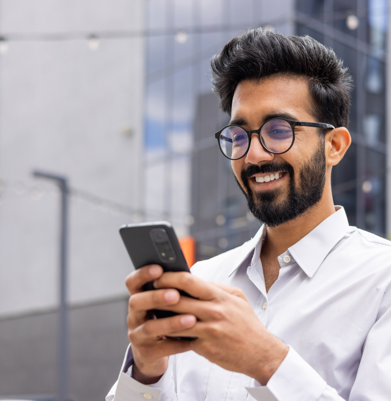 Man typing on phone outside office building